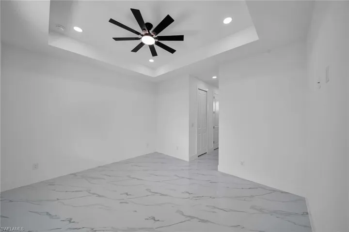 Unfurnished room featuring recessed lighting, a ceiling fan, light marble finish flooring, and a raised ceiling