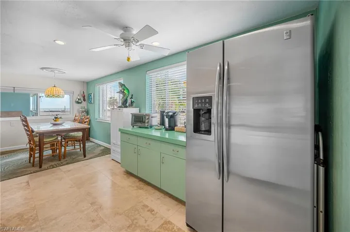 Kitchen featuring stainless steel fridge, ceiling fan, light countertops, and decorative light fixtures