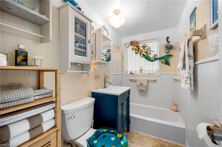 Bathroom featuring tile walls, vanity, and tasteful backsplash