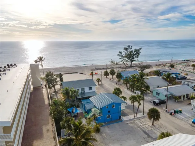 Coastal property with direct beach access, featuring a vibrant blue exterior, a metal roof, and an elevated entrance
