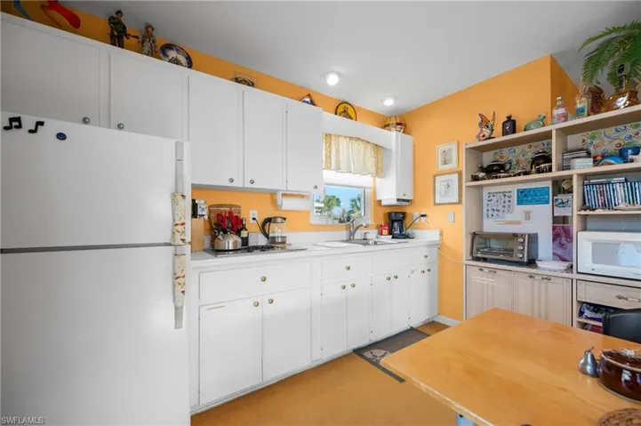 Kitchen with white appliances, light countertops, and white cabinets