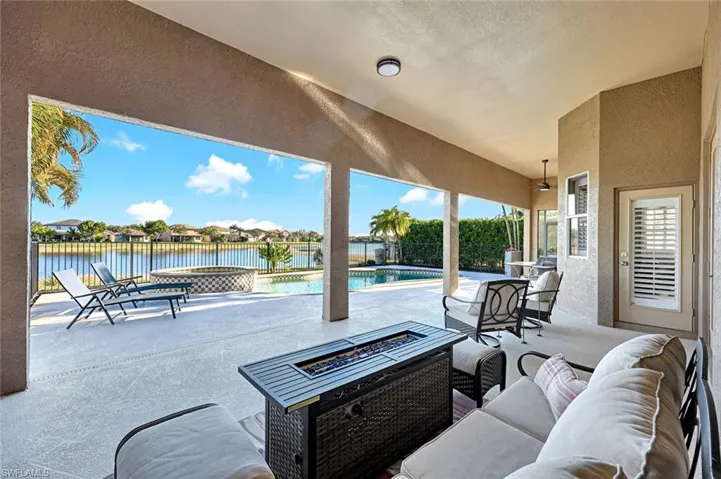 Fenced backyard featuring a patio, a residential view, a pool with connected hot tub, a water view, and an outdoor living space with a fire pit