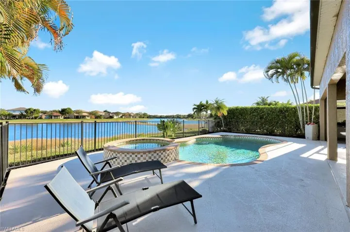 View of swimming pool featuring a patio area, a pool with connected hot tub, and a water view