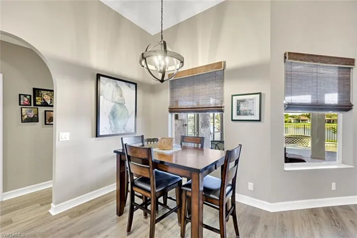 Dining room with arched walkways, light wood finished floors, and a chandelier