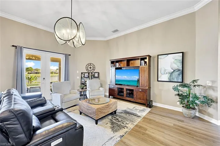 Living room featuring light wood-type flooring, french doors, crown molding, and a chandelier