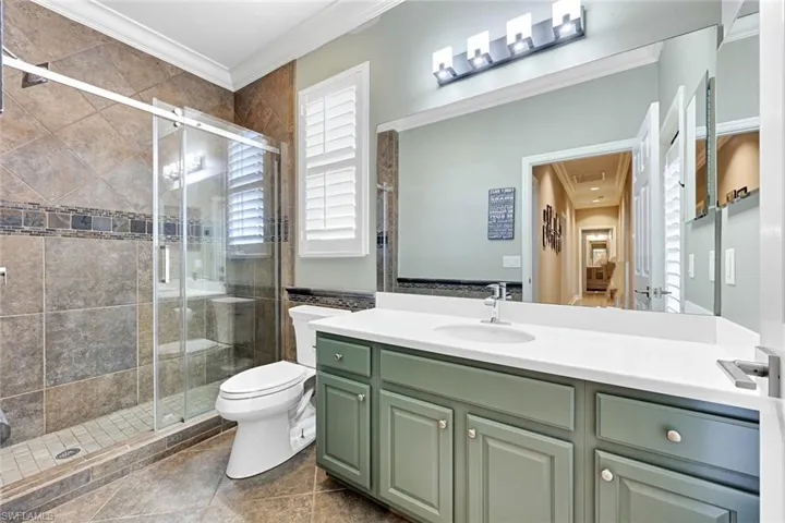 Full bathroom with crown molding, vanity, and a stall shower