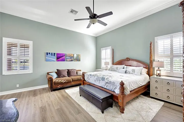 Bedroom featuring light wood-style floors, ornamental molding, and a ceiling fan