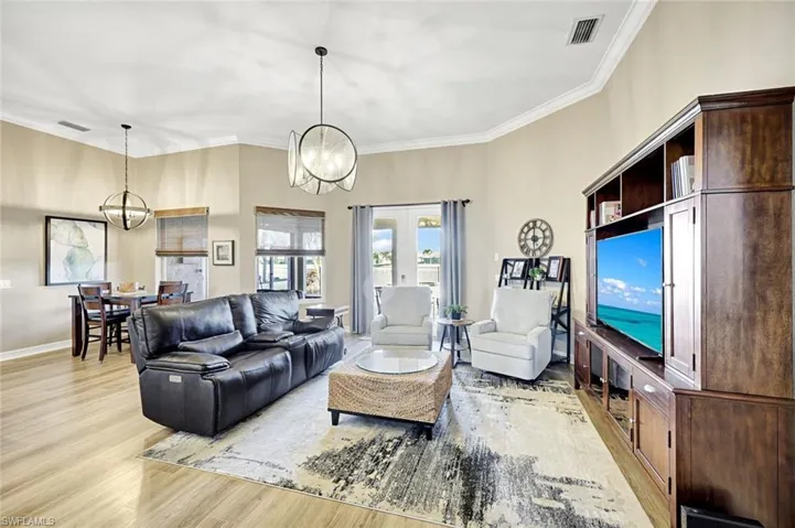 Living area with light wood-style flooring, a chandelier, crown molding, and french doors