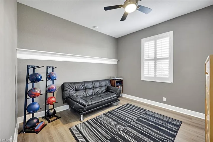 Guest bedroom 3 is being used as a sitting room with light wood-style floors and a ceiling fan