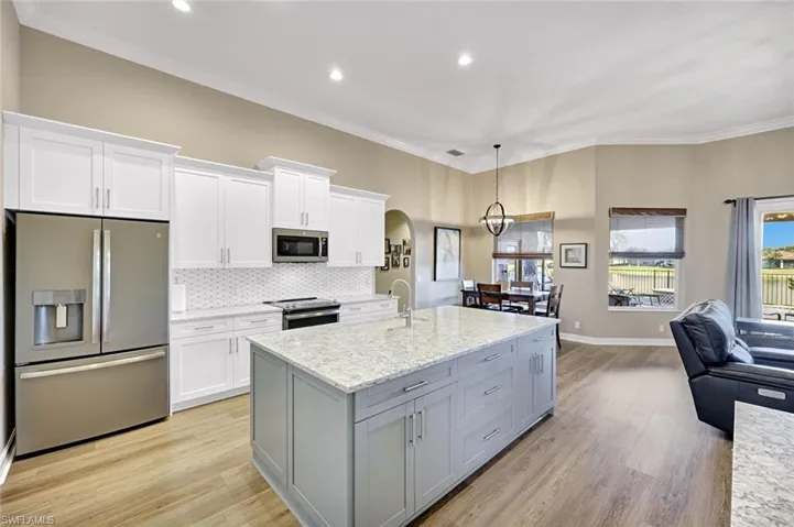 Kitchen featuring stainless steel appliances, open floor plan, white cabinetry, hanging light fixtures, and recessed lighting