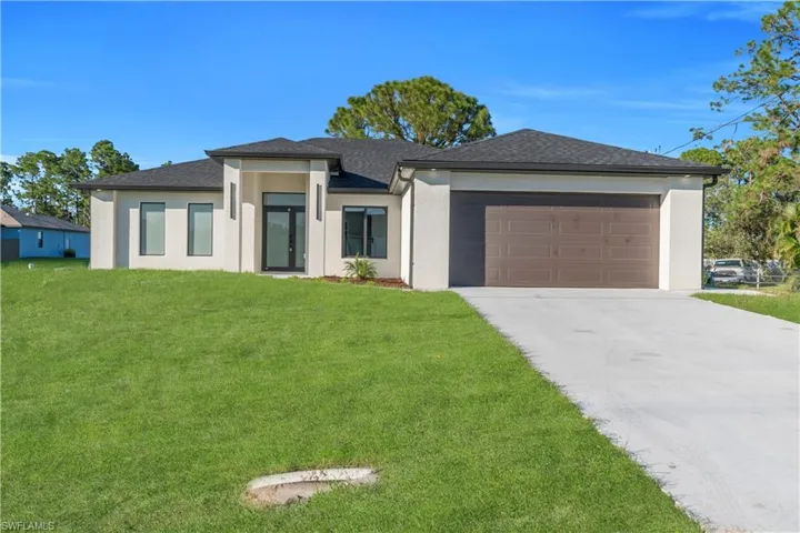Prairie-style house featuring a front lawn, stucco siding, concrete driveway, a shingled roof, and a garage