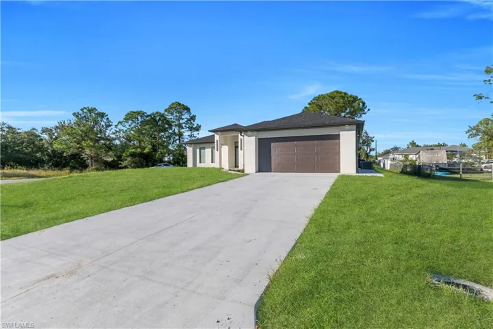 View of front of house with driveway, stucco siding, a front yard, and a garage