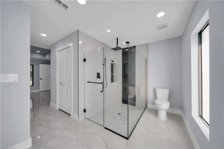 Full bath with a shower stall, recessed lighting, and light marble finish flooring
