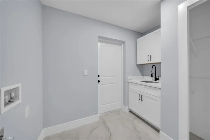 Laundry area with hookup for a washing machine and light marble finish flooring