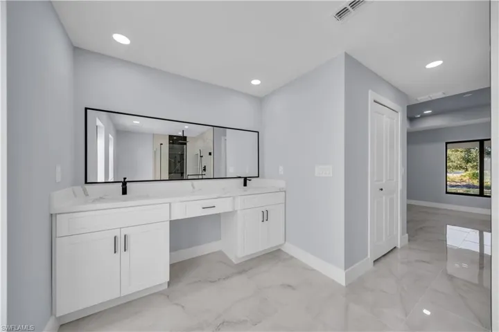 Full bath featuring light marble finish flooring, double vanity, a marble finish shower, and recessed lighting