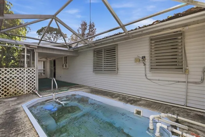 View of swimming pool featuring a sunroom, patio surround, a lanai, and a jacuzzi