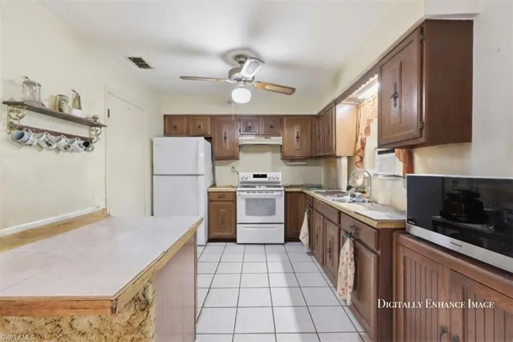 Kitchen with white appliances, light countertops, light tile patterned flooring, and a ceiling fan