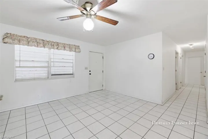 Empty room with a ceiling fan and light tile patterned flooring