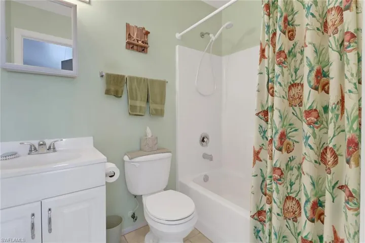 Full bathroom with toilet, vanity, tile patterned floors, and shower / bath combination with curtain