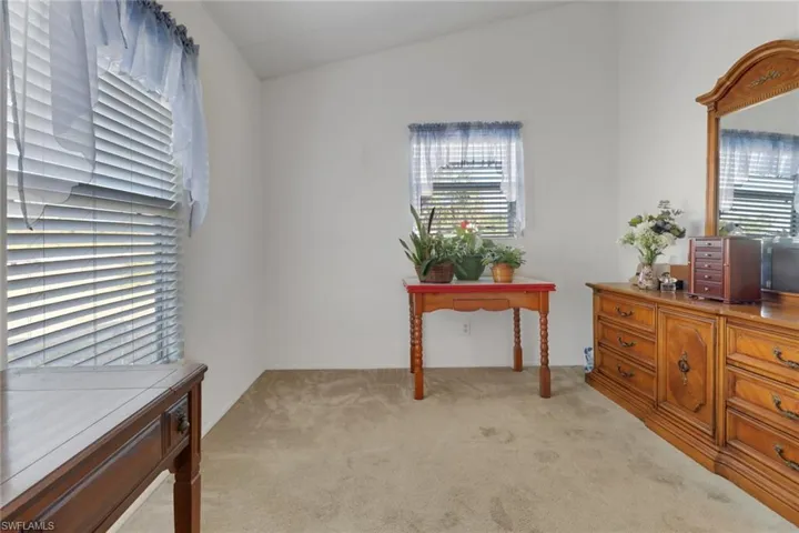 Home office featuring lofted ceiling and light carpet