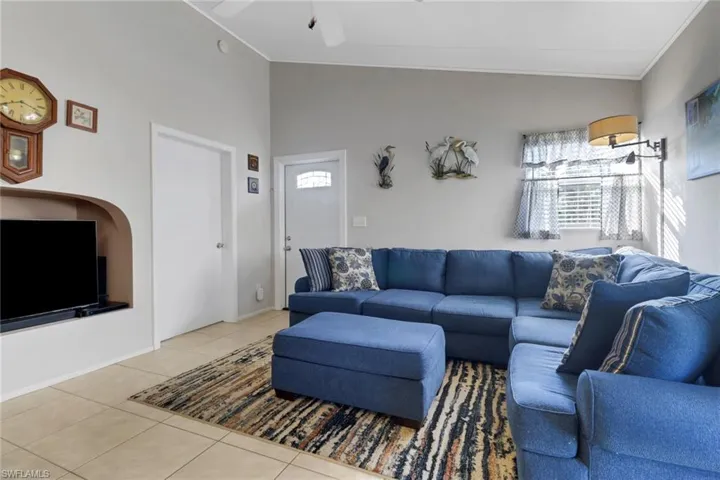 Living room featuring tile patterned floors, ceiling fan, and crown molding