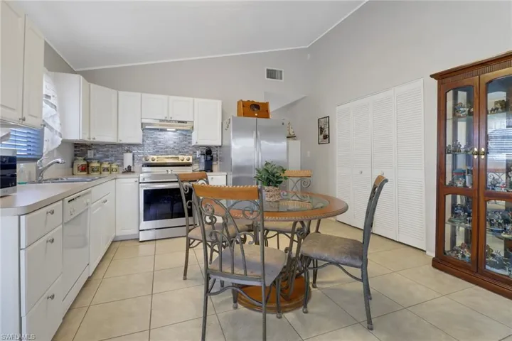 Kitchen featuring lofted ceiling, stainless steel appliances, white cabinetry, and sink