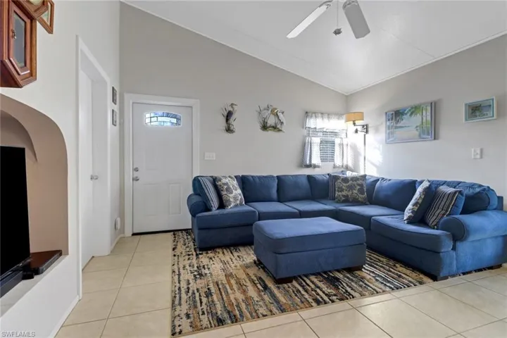 Tiled living room with ceiling fan and vaulted ceiling