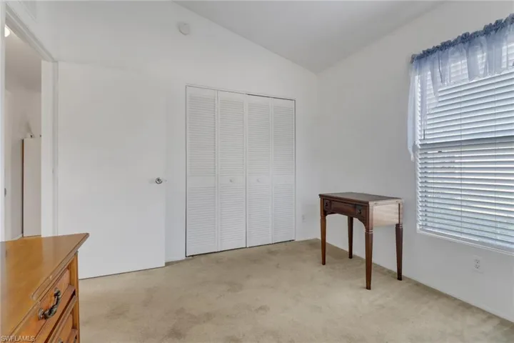 Carpeted bedroom with lofted ceiling and a closet