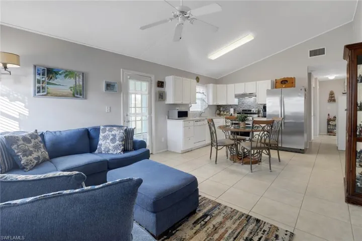 Living room with ceiling fan, vaulted ceiling, and light tile patterned floors