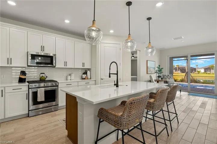 Kitchen with sink, white cabinetry, stainless steel appliances, and a kitchen island with sink