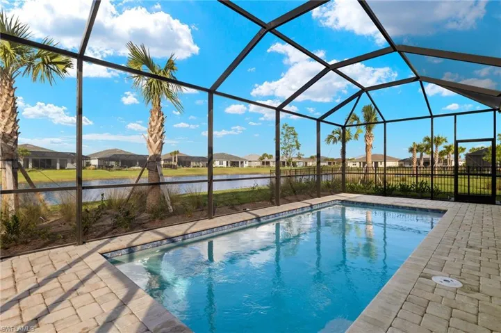 View of swimming pool with a lanai, a patio area, and a water view