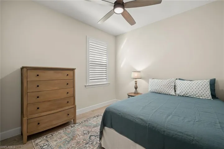 Bedroom with light wood-style tile floors and ceiling fan
