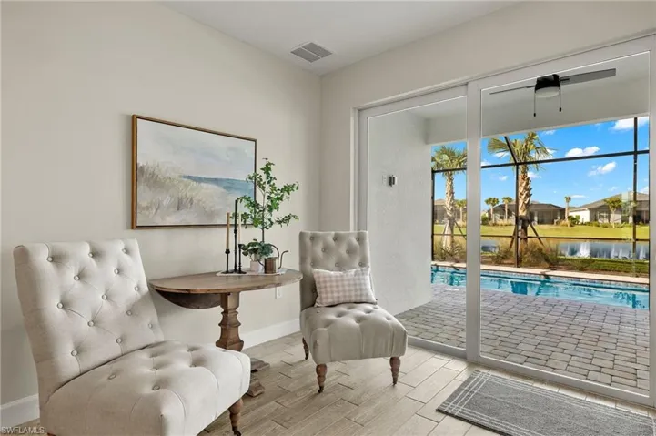 Sitting area featuring ceiling fan, a pool view, and light wood-style tile flooring