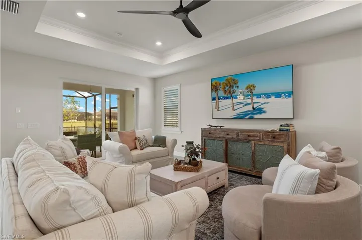 Living room featuring a tray ceiling, ceiling fan, and ornamental molding