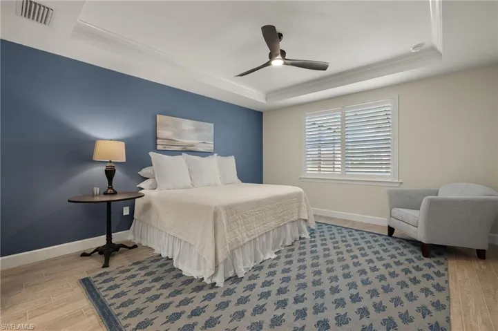 Bedroom featuring a tray ceiling, ceiling fan, light hardwood / wood-style flooring, and ornamental molding