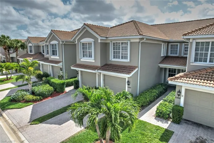 View of front of house with stucco siding, an attached garage, a tiled roof, a residential view, and driveway