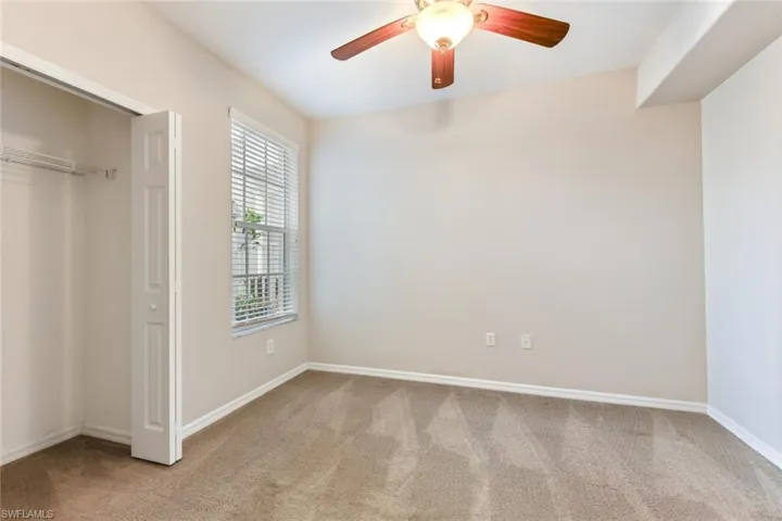 Unfurnished bedroom with a closet, carpet flooring, baseboards, and a ceiling fan