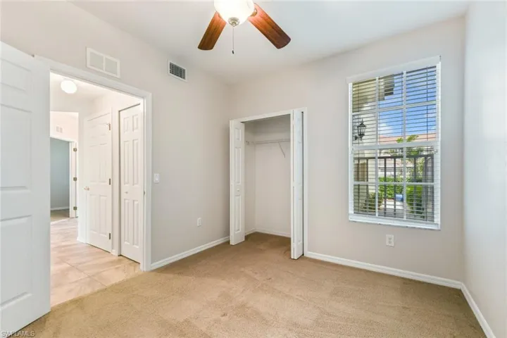 Unfurnished bedroom with baseboards, visible vents, a ceiling fan, and light colored carpet