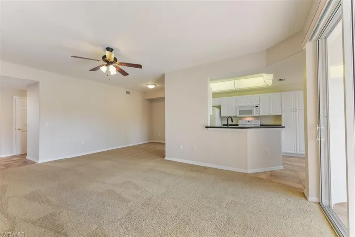 Unfurnished living room with light carpet, baseboards, a sink, and a ceiling fan