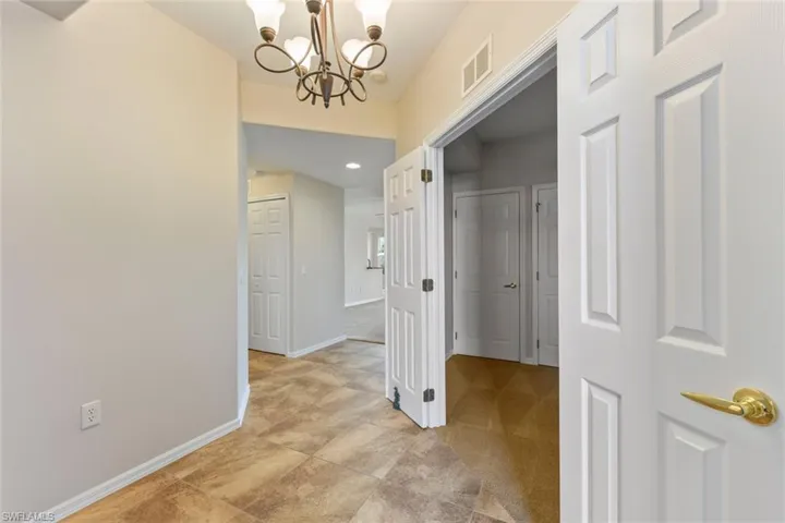 Corridor with an inviting chandelier, baseboards, and visible vents