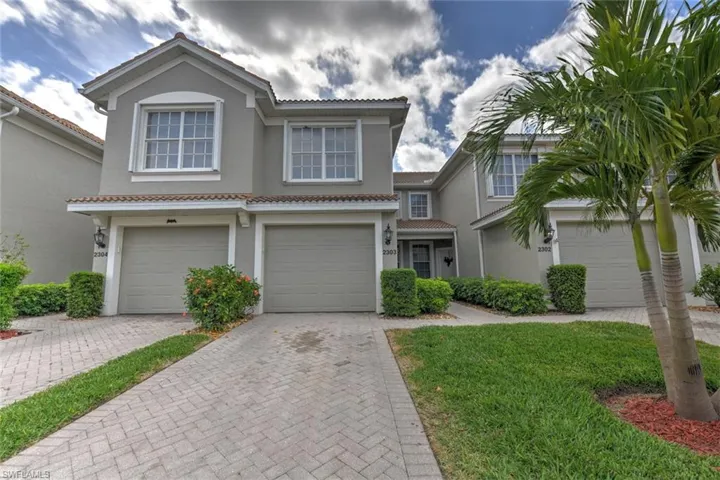 View of front facade with a tiled roof, stucco siding, driveway, and a garage