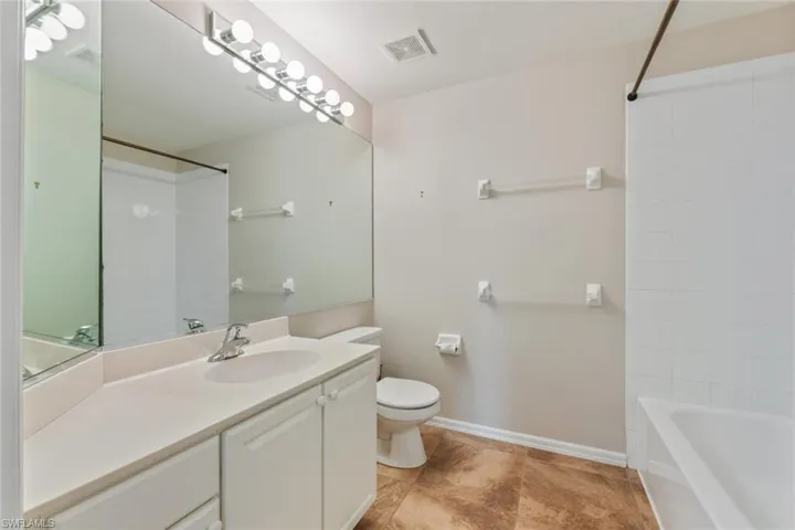 Full bathroom with visible vents, washtub / shower combination, baseboards, toilet, and vanity