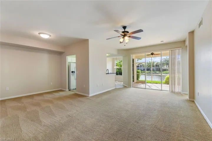 Unfurnished living room featuring visible vents, carpet, baseboards, and ceiling fan