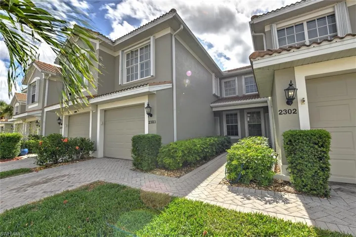 View of front of property featuring driveway, stucco siding, a tile roof, and a garage