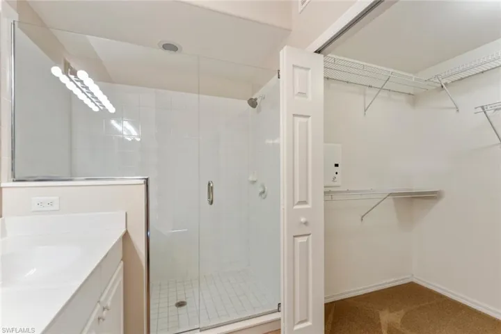 Full bathroom with baseboards, vanity, a spacious closet, and a shower stall
