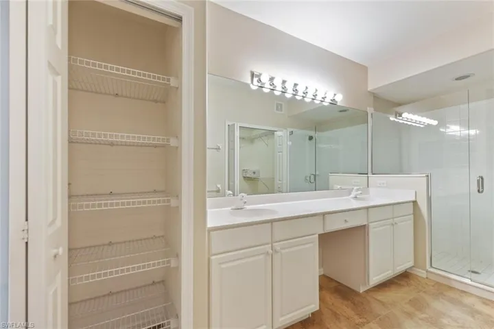 Bathroom featuring a spacious closet, double vanity, a sink, and a shower stall
