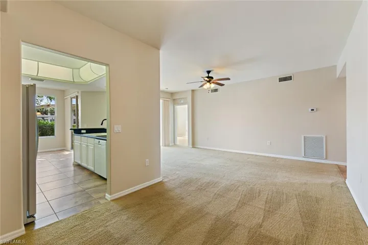 Unfurnished room with ceiling fan, light colored carpet, and visible vents