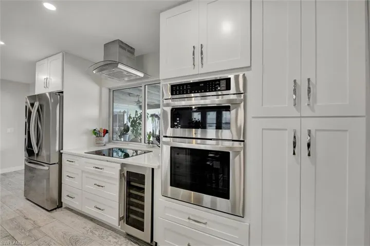 Kitchen featuring light wood-style floors, white cabinets, appliances with stainless steel finishes, light countertops, and beverage cooler