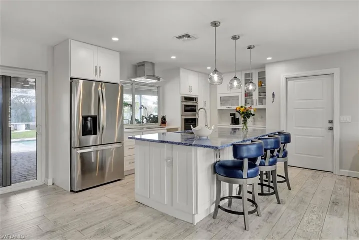 Kitchen with dark stone counters, glass insert cabinets, white cabinets, appliances with stainless steel finishes, and a sink