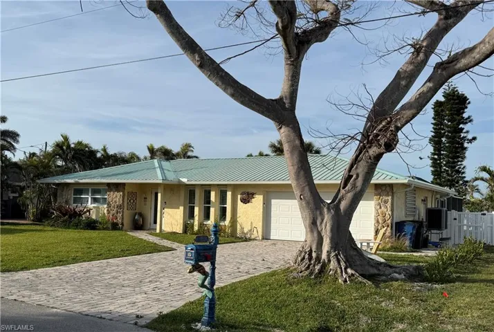 Single story home with an attached garage, stucco siding, a front lawn, decorative driveway, and metal roof